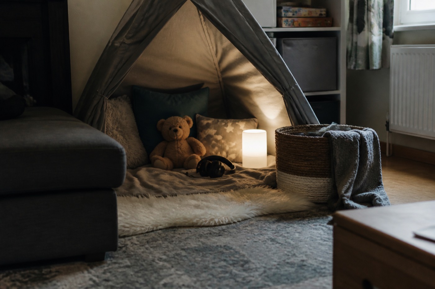 A calm corner with cushions, a blanket, headphones and a teddy — a recovery space set up before it is needed.